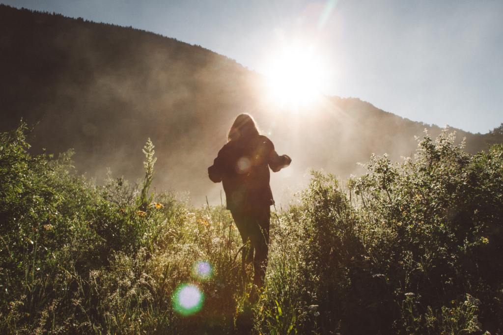 Woman walking towards mountain and sunlight – visit Pandora's Health