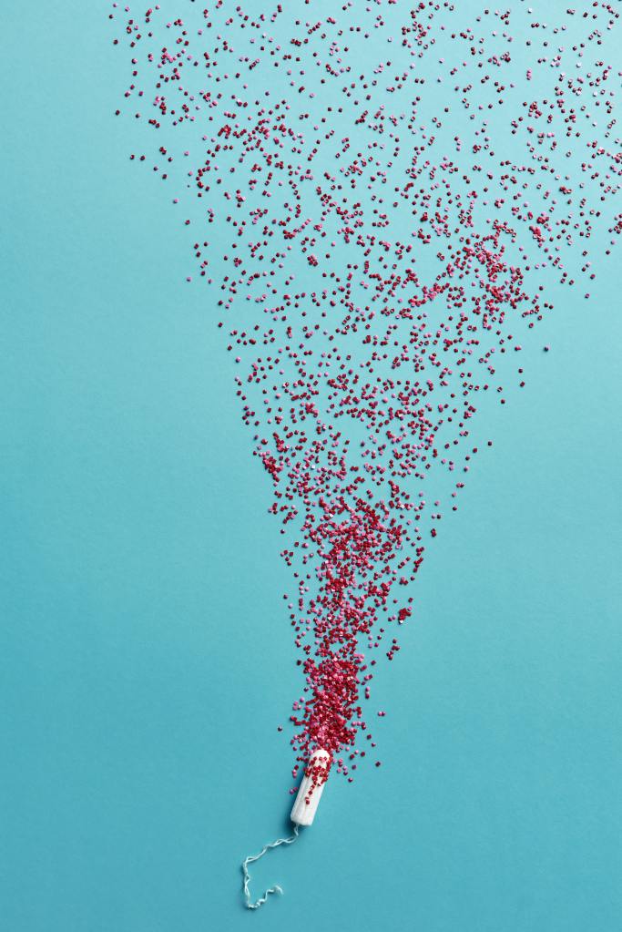 A tampon lying on a bright blue background, with red confetti spraying from it.
Pandora's Health Blog