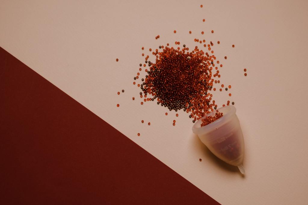 A silicone menstrual cup with small red beads pouring out of it.
Pandora's Health Blog