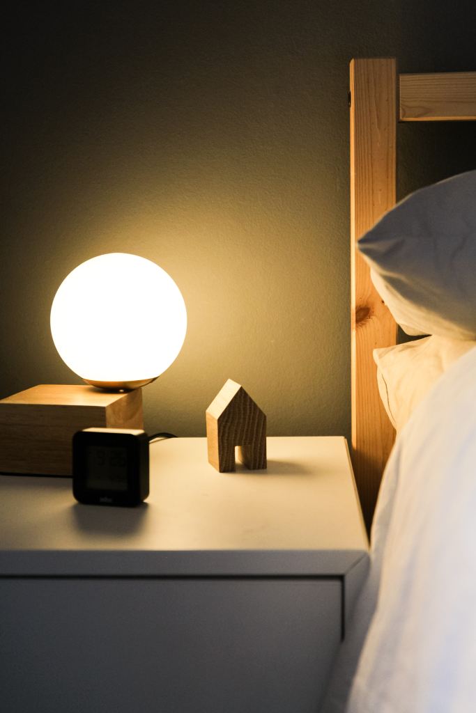 A bedside table with a small wooden toy home and round lamp. 

Pandora's Health blog.

Image courtesy of Unsplash.
